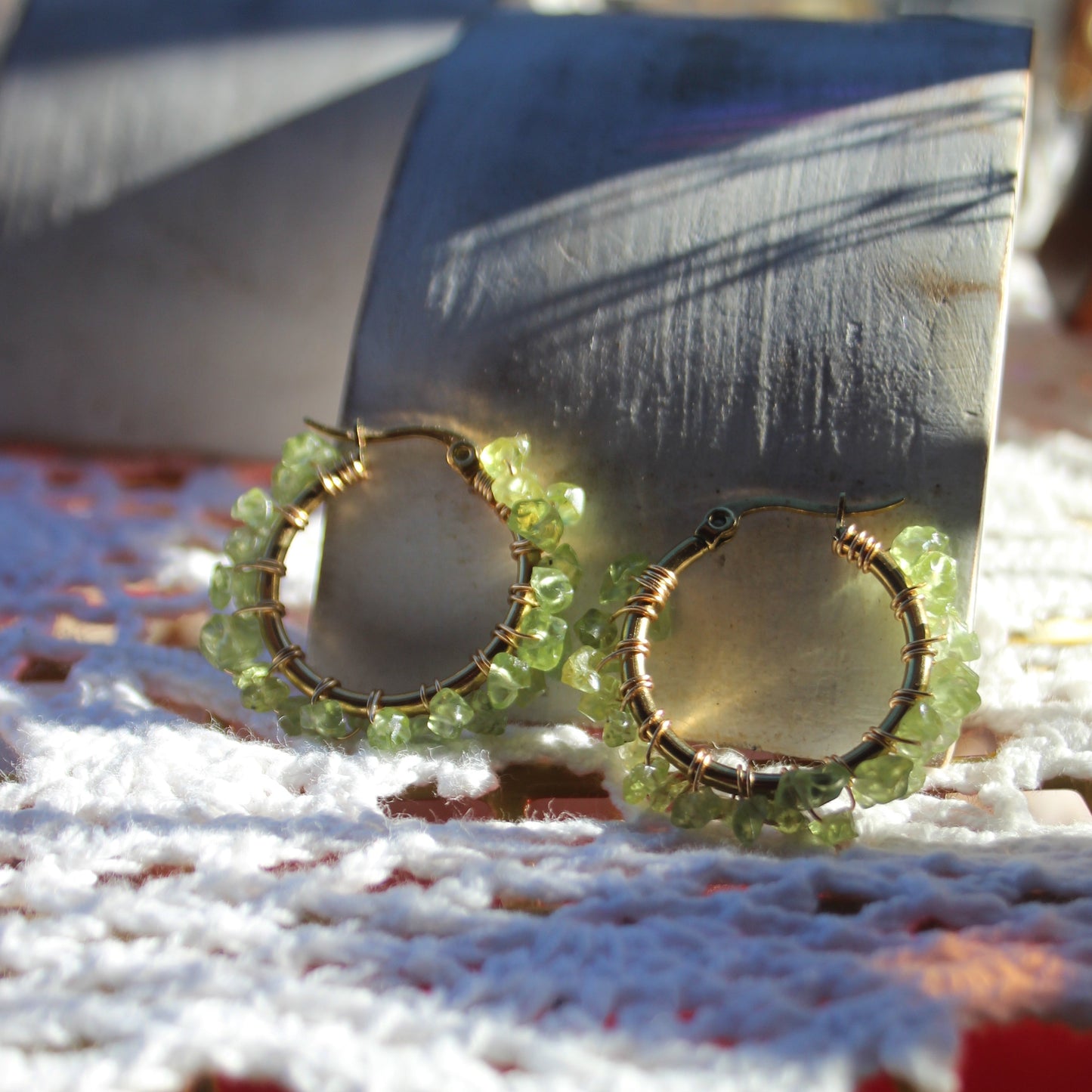 Close-up of handmade peridot hoop earrings showing small green peridot stones set in gold plated stainless steel