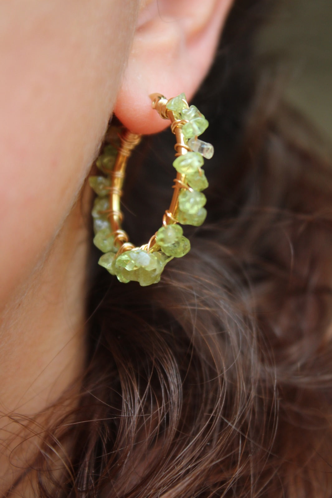 Handmade peridot hoop earrings worn on ear, showing vibrant green stones and 18K gold plated hoops